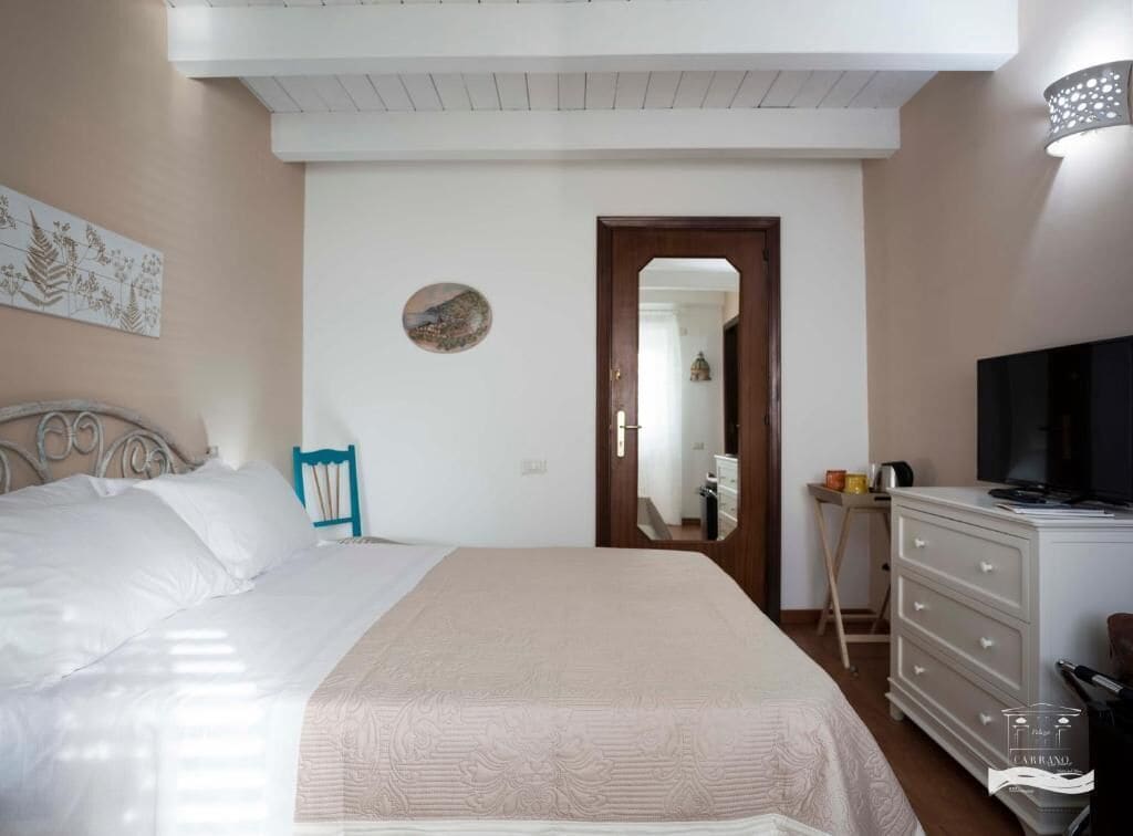 A bedroom with a bed, dresser, television, and a mirror.