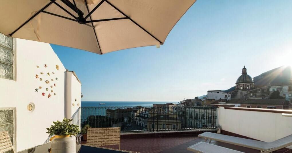 Una terraza en la azotea con vistas a una ciudad costera, incluyendo un edificio de forma abovedada.
