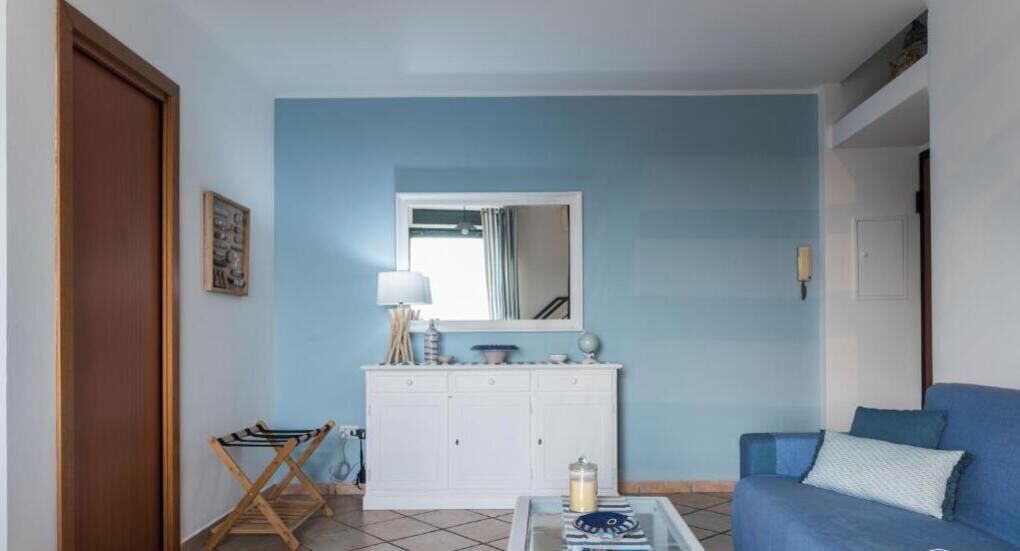 A living room with a blue wall, a white cabinet, a blue sofa, and a wooden door.