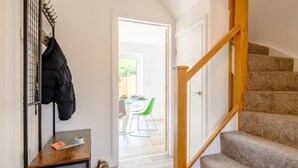 Eine Treppe mit hölzernen Geländern, ein Kleiderständer mit einer Jacke und ein Tisch mit einer Zeitschrift und einem Schuhpaar.