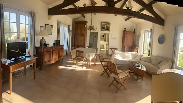 Un salon spacieux avec un plafond haut, des meubles en bois, un coin repas et de grandes fenêtres.