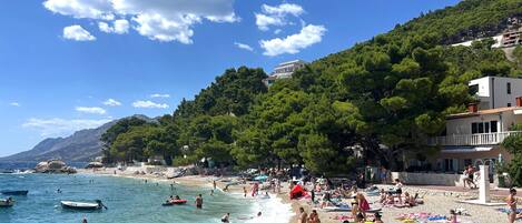 A beach with people, boats, and buildings.