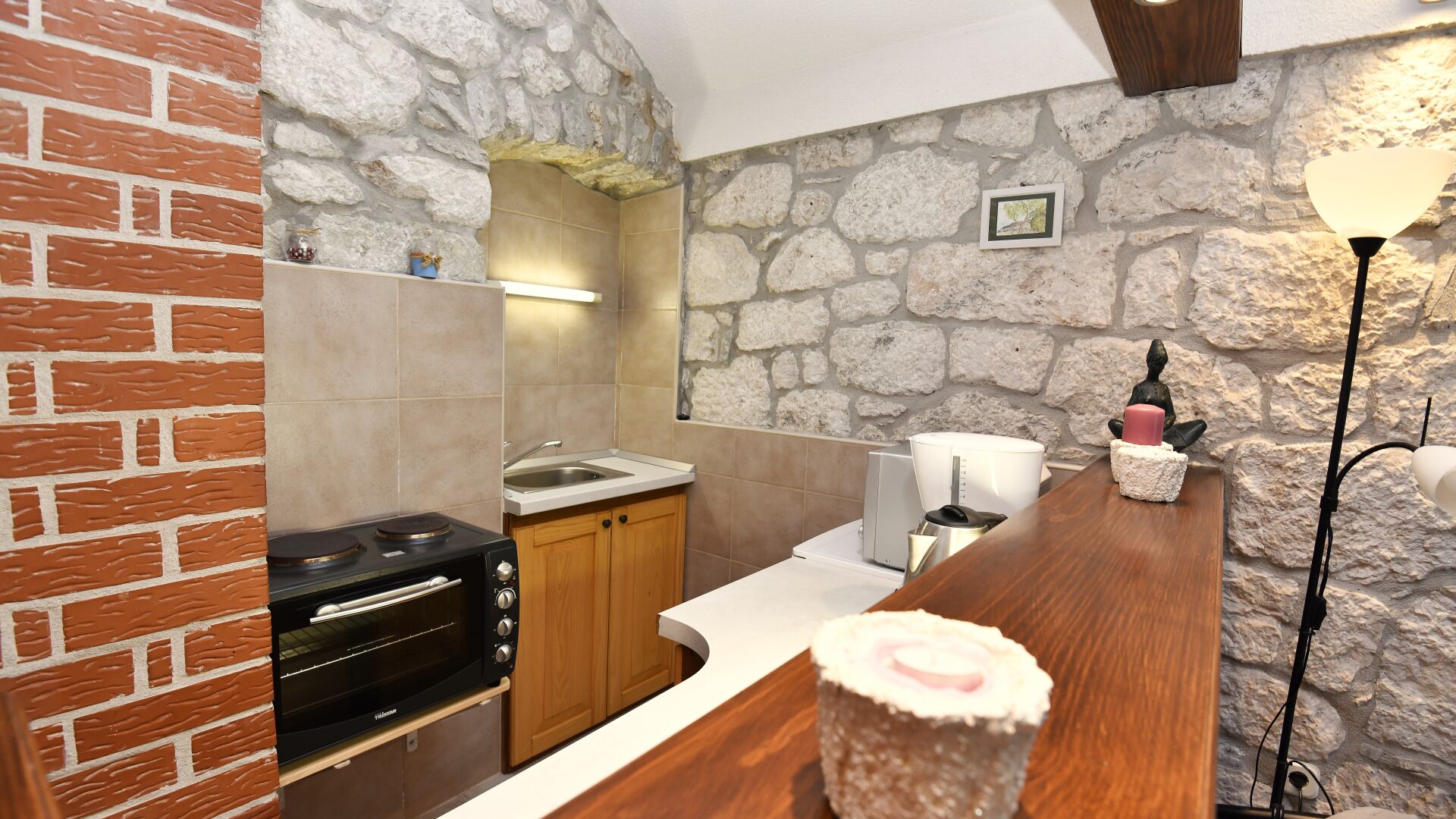 Una cucina con parete in pietra, parete in mattoni, piano di lavoro in legno e forno a incasso.