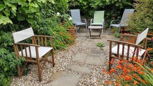 A garden pathway with chairs and a table, surrounded by greenery and flowers. - 3 Bed in Weymouth (oc-87065) (Weymouth)