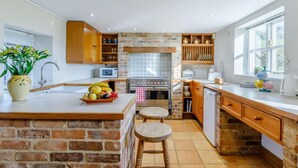A kitchen with a brick island, wooden cabinets, a stove, and a window. - 3 Bed in Weymouth (oc-87065) (Weymouth)