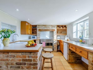 A kitchen with a brick island, wooden cabinets, a stove, and a window. - 3 Bed in Weymouth (oc-87065) (Weymouth)