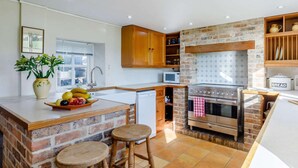 A kitchen with a brick backsplash, wooden cabinets, a built-in oven, and a fruit bowl on the counter. - 3 Bed in Weymouth (oc-87065) (Weymouth)