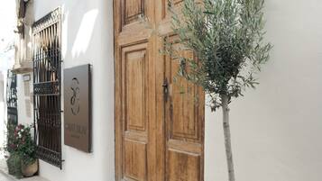 Un bâtiment avec une porte en bois et un arbre en pot.