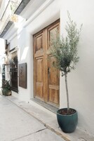 Un edificio con una puerta de madera y un árbol en maceta.