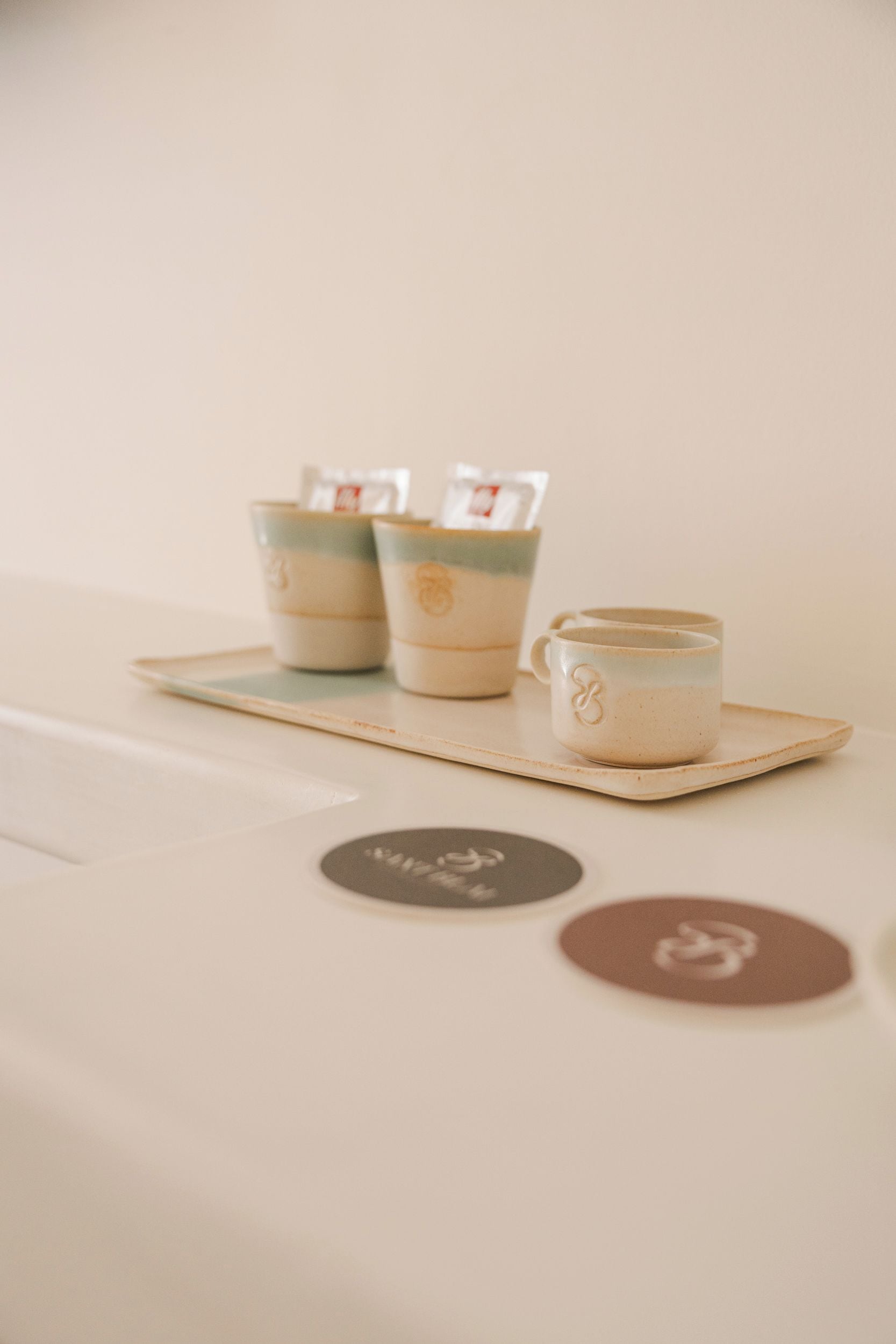 Un plateau avec trois tasses en céramique et une petite assiette, probablement dans un hôtel.