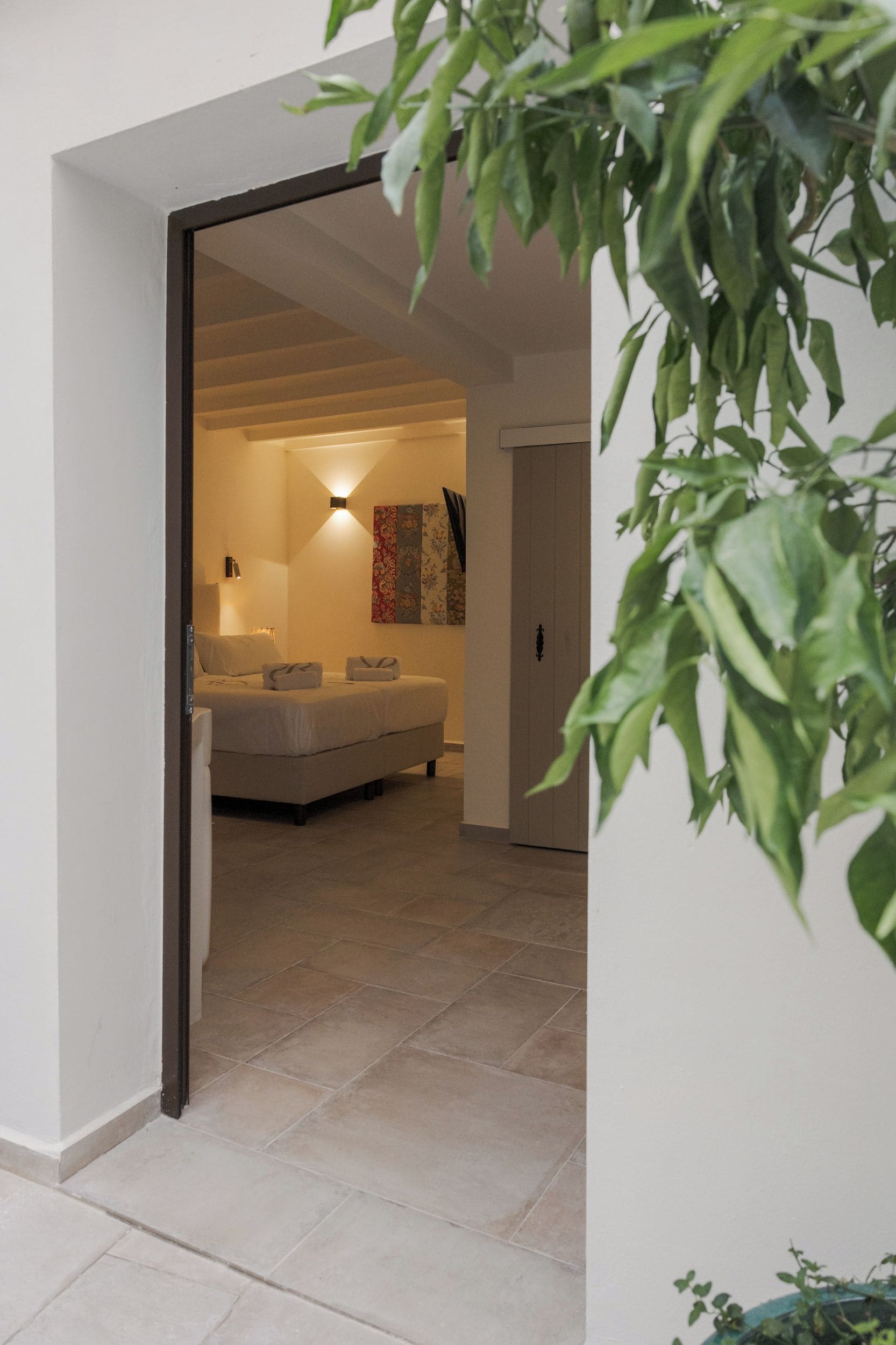 A modern interior with a bed, bedside tables, a wall-mounted light, and a decorative piece.