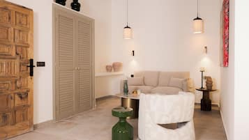 Una habitación con puerta de madera, un sofá color beige, una mesita y una botella verde.