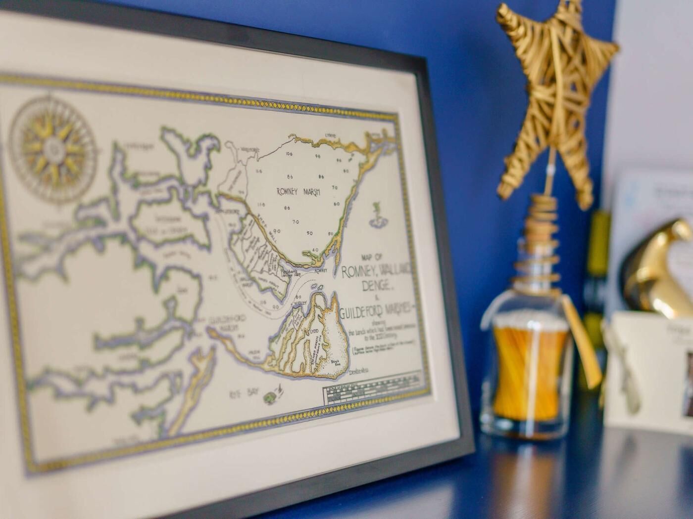 A framed map of Romney, Wallingford, and Denge with a compass rose.