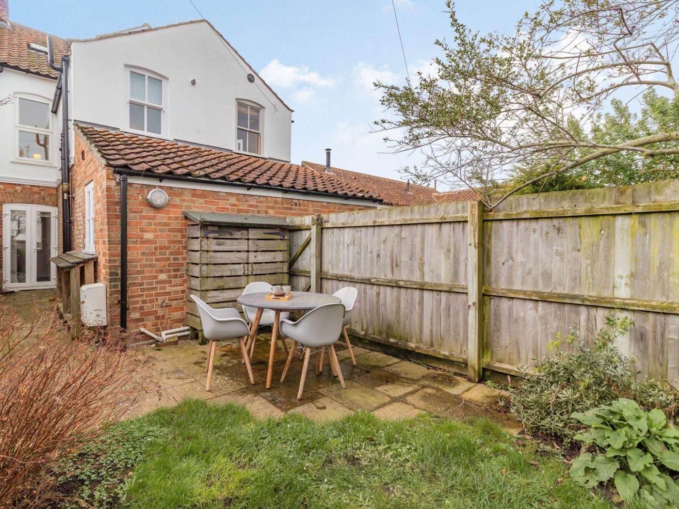 A patio with a table and chairs, a wooden fence, and a brick wall.