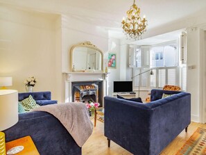 Ein Wohnzimmer mit zwei Sofas, einem Kamin, einer Chandelüster und einem großen Spiegel.