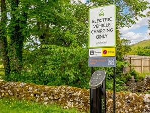 An electric vehicle charging station with a sign indicating it's for electric vehicles only, a no parking sign, and a charging point with a display. - 2 Bed in Skipton (oc-87370) (Kettlewell)