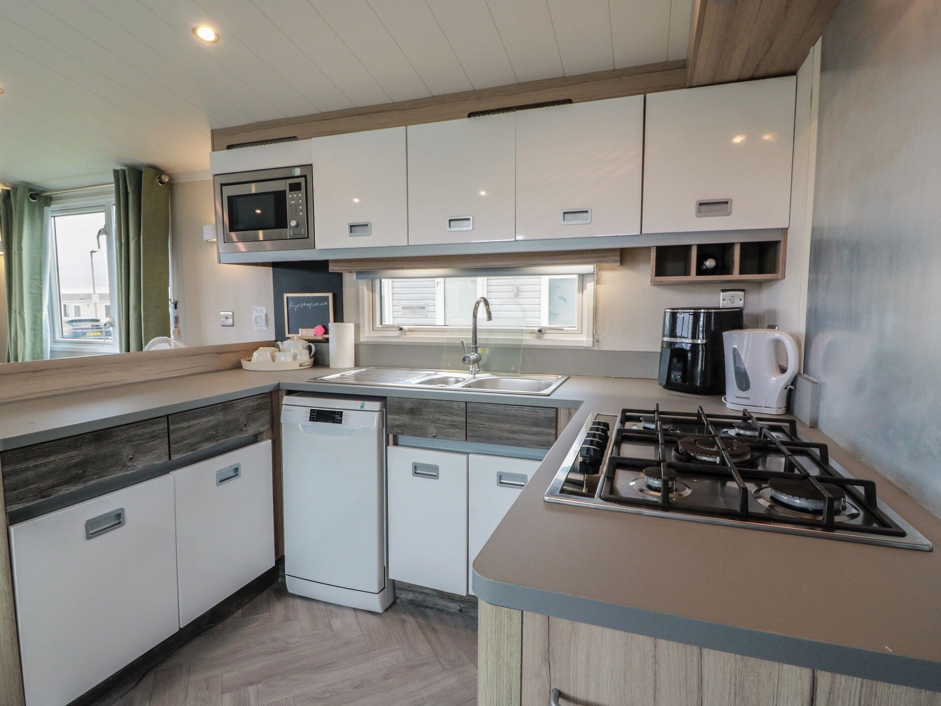 A compact kitchen with a microwave, sink, dishwasher, and stove.
