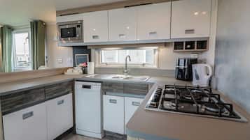 A compact kitchen with a microwave, sink, dishwasher, and stove.