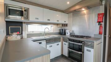 A modern kitchen with a built-in microwave, gas stove, oven, and a sink with a window above.