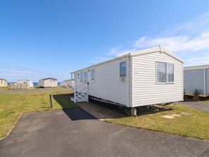 A white mobile home with a small porch and steps, located in a caravan park with other similar homes. - Craig Tara Holiday Park 101 Bay View (Ayr)