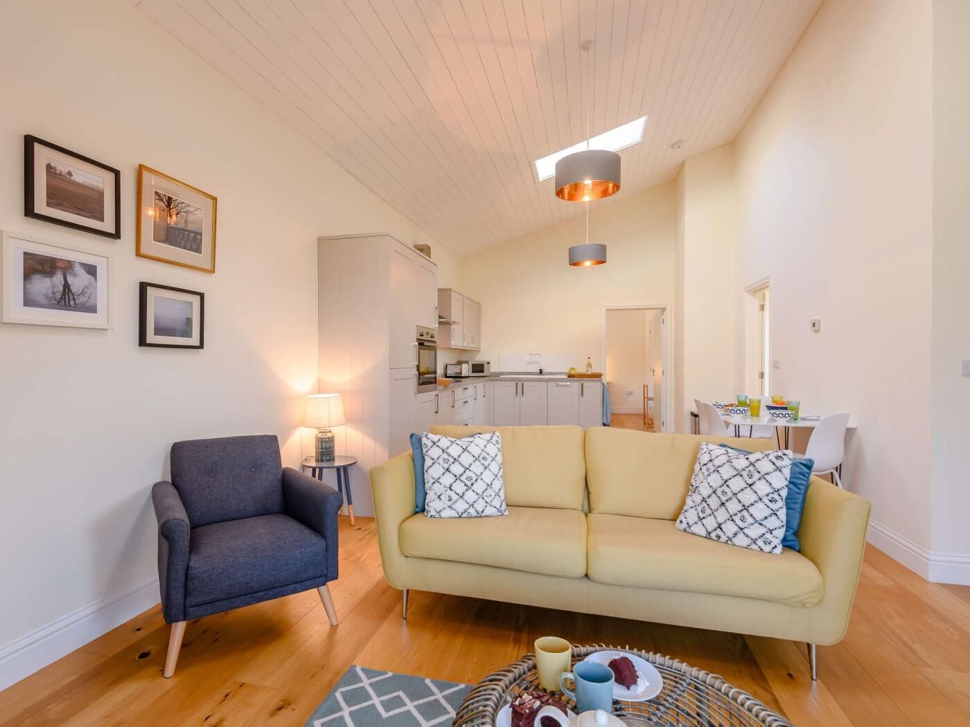 A living room with a sofa, armchair, and a dining area with a table and chairs.