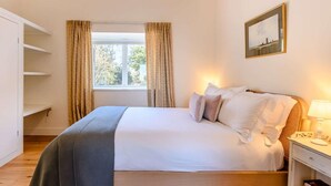 A bedroom with a bed, a bedside table, a nightstand, a window with curtains, and a wall-mounted picture. - 2 Bed in Norwich (oc-87511) (Colby)
