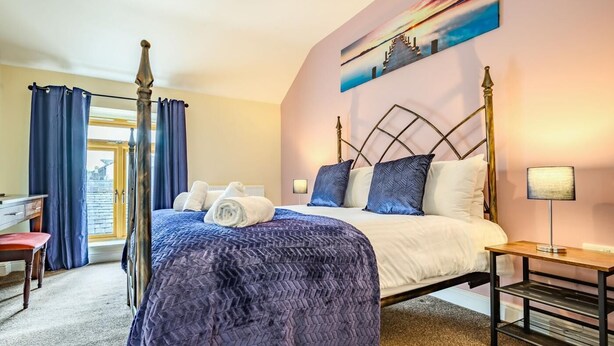 A bedroom with a bed, a desk, a chair, a nightstand, and a painting on the wall. - 1 Bed in Cockermouth (oc-87480) (Cockermouth)