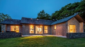 A stone house with large windows, a well-maintained lawn, and a clear sky. - 3 Bed in Saltash (oc-87716) (Saint Mellion)