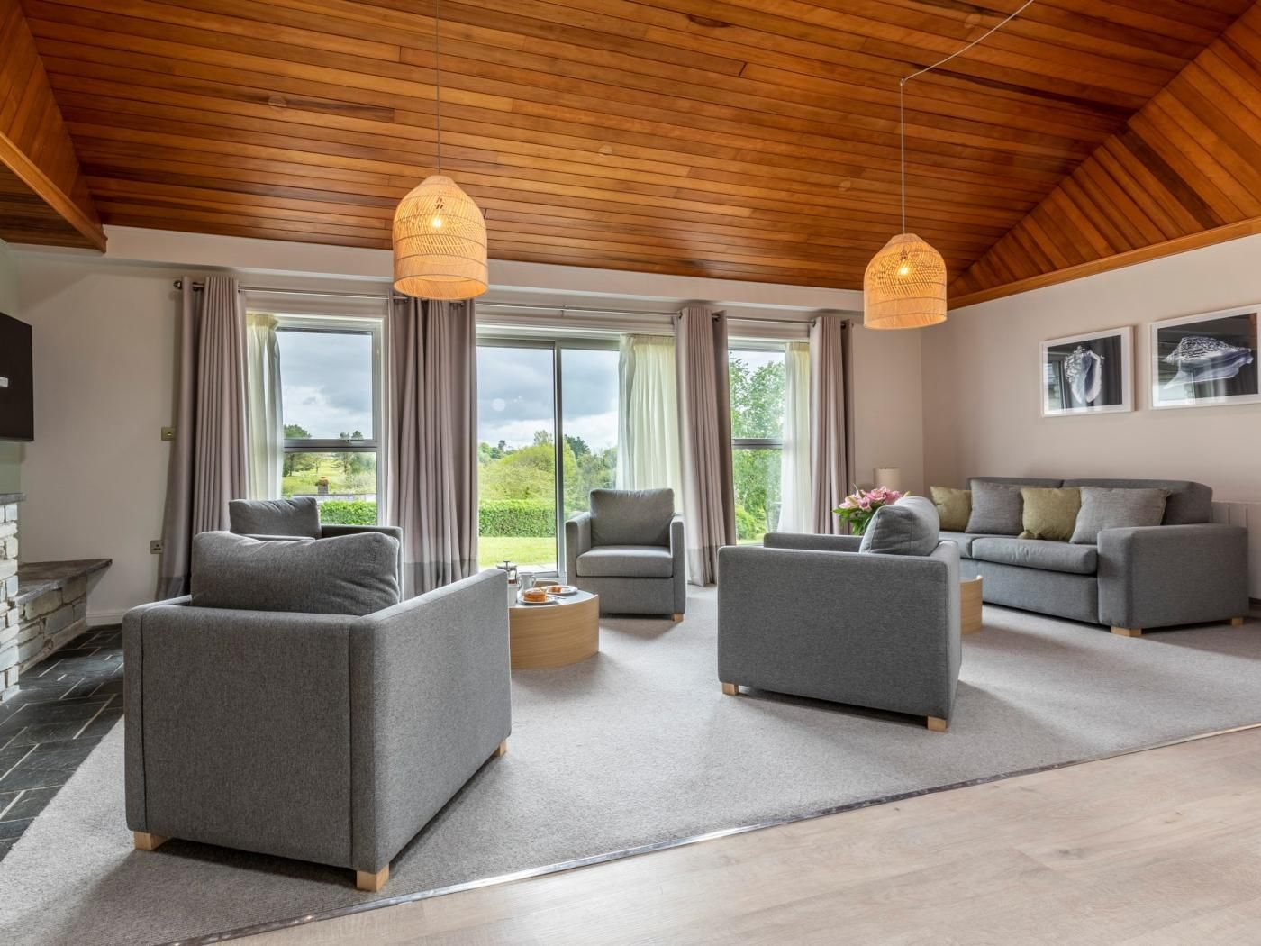 A spacious living room with a high ceiling, grey sofas, a coffee table, and a fireplace.