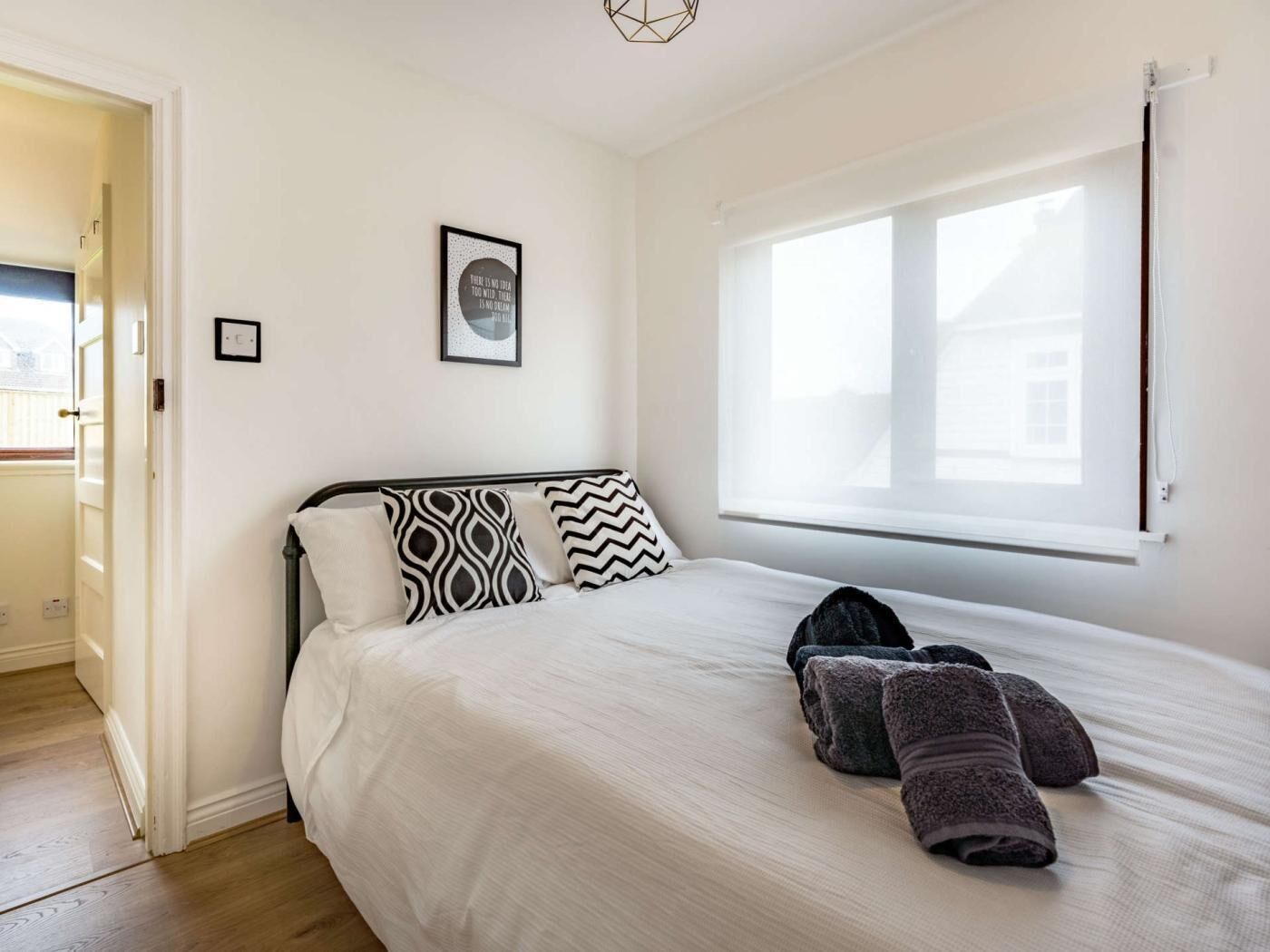 A bedroom with a bed, pillows, a window, and a door.