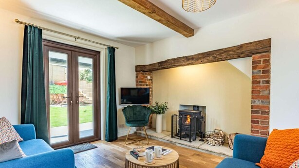 Ein Wohnzimmer mit Kamin, zwei Sofas, einem Fernseher und Holzboden.