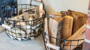 Zwei Drahtkörbe voller Holzscheite.
