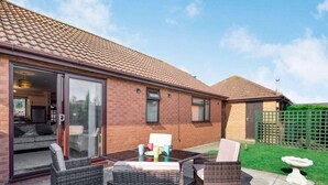 A residential property with a patio area featuring wicker furniture, a sliding glass door leading to an interior space, and a brick exterior. - 2 Bed in Mablethorpe (oc-87801) (Mablethorpe)