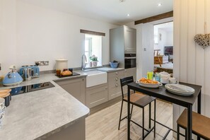 Una cocina moderna con una isla central, una zona de comedor con mesa y sillas, y vista al espacio de estar contiguo.