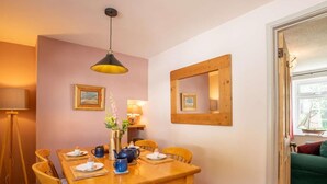 A dining area with a wooden table, chairs, a hanging light fixture, and framed pictures on the wall. - 2 Bed in Lowestoft (oc-88109) (Lowestoft)