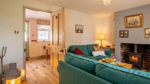 A cozy living room with a green sofa, a fireplace, and a dining area with a table and chairs. - 2 Bed in Lowestoft (oc-88109) (Lowestoft)