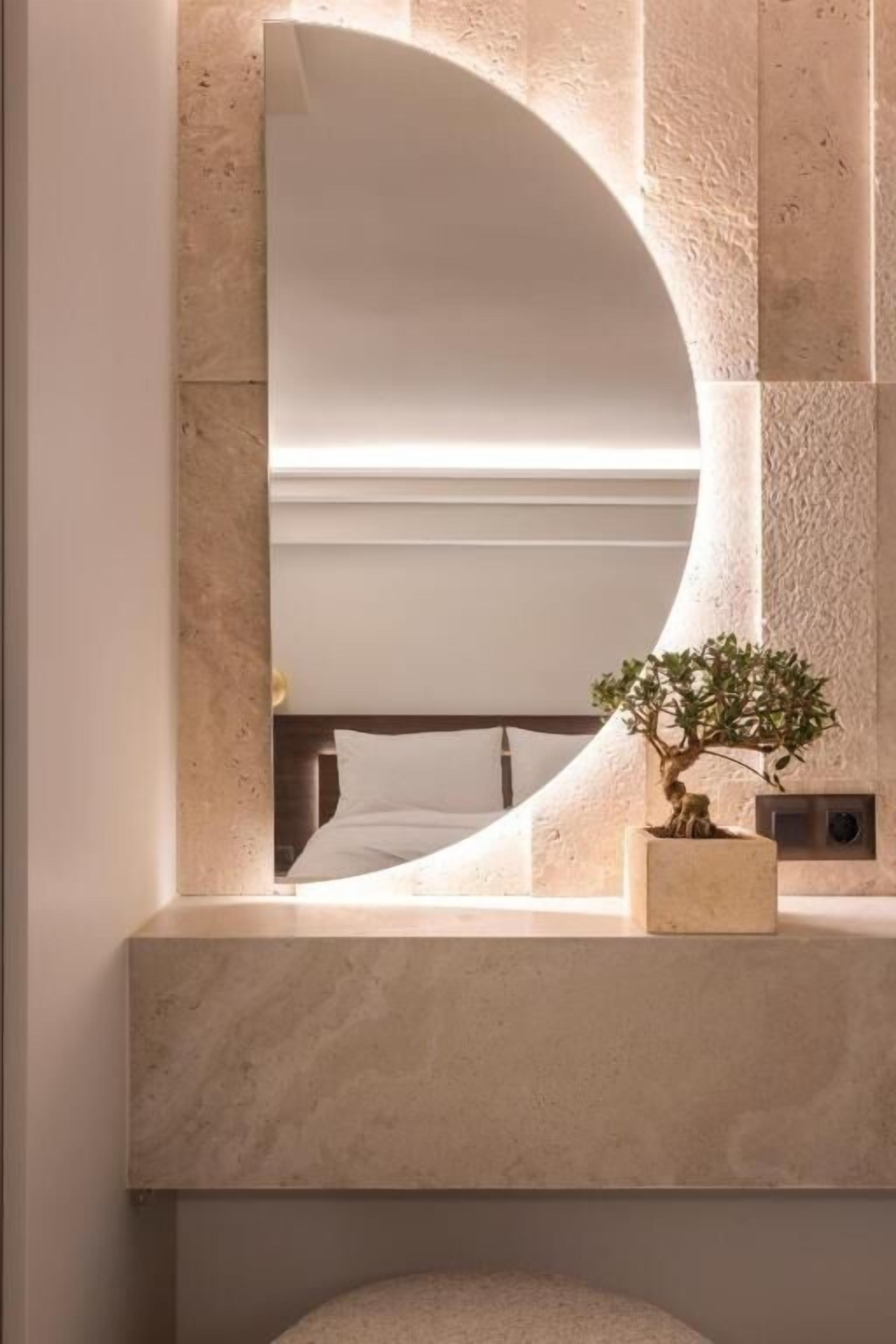 A bathroom vanity with a large mirror, a potted plant, and a built-in bench.