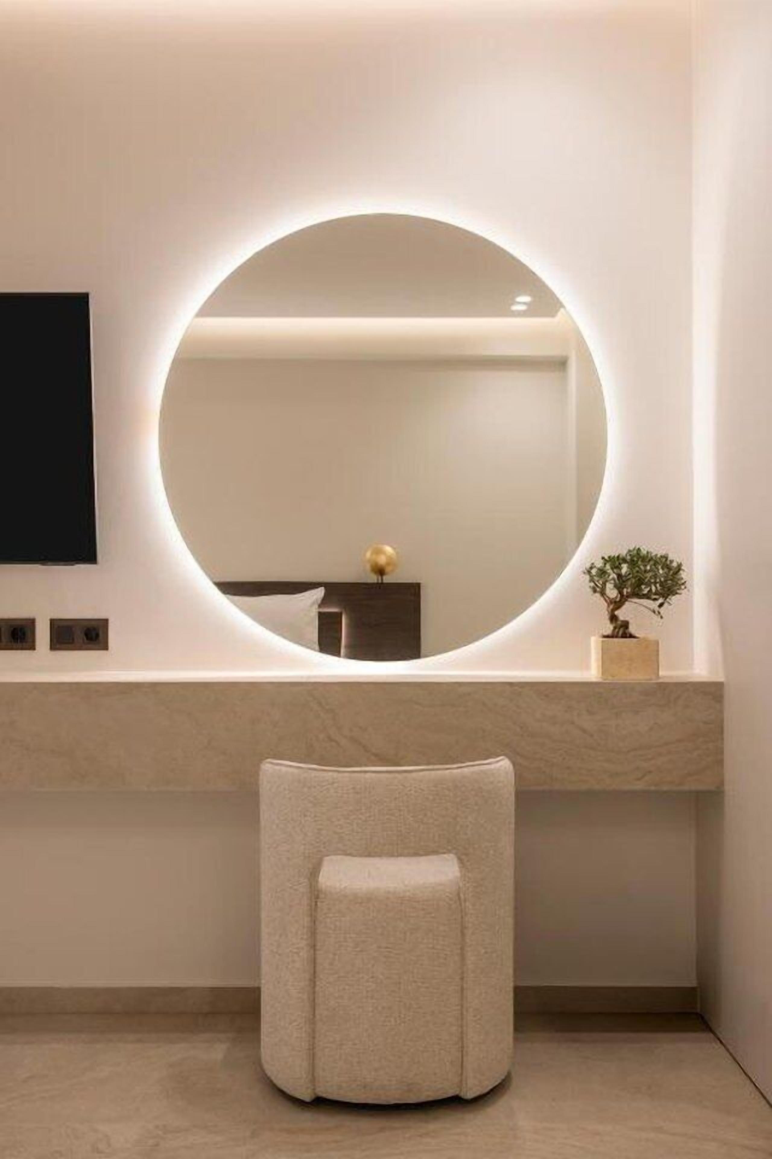 A bathroom with a round mirror, a small stool, and a potted plant.