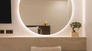 A bathroom with a round mirror, a small stool, and a potted plant.