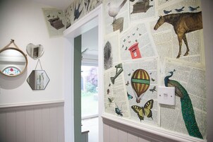 A wall with a newspaper collage including birds, a peacock, and a hot air balloon.