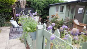 A garden with a wooden fence, a chair, and a shed. - Snug Corner (Holmfirth)