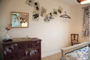 Un dormitorio con cómoda, cama, espejo y adornos en la pared.