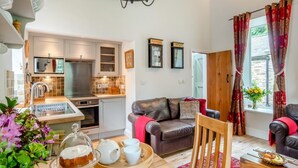 A modern kitchen with a built-in oven, a dining area with a wooden table, and a cozy living room with a leather sofa. - 2 Bed in Hexham (oc-88032) (Once Brewed)