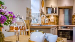 A kitchen with a cake on a glass stand, white teapot, and cups on a tray. - 2 Bed in Hexham (oc-88032) (Once Brewed)