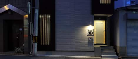 A modern multi-story building with a flat facade, multiple windows, and a visible entrance.