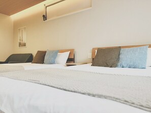 A hotel room with two beds, a chair, a bedside table, and a wall-mounted light fixture. - Koti Sopo Universal Bay 4 by Liaison (Minato ward)