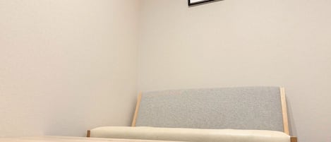 Una habitación minimalista con una cama, una cita inspiradora enmarcada en la pared y un termostato.