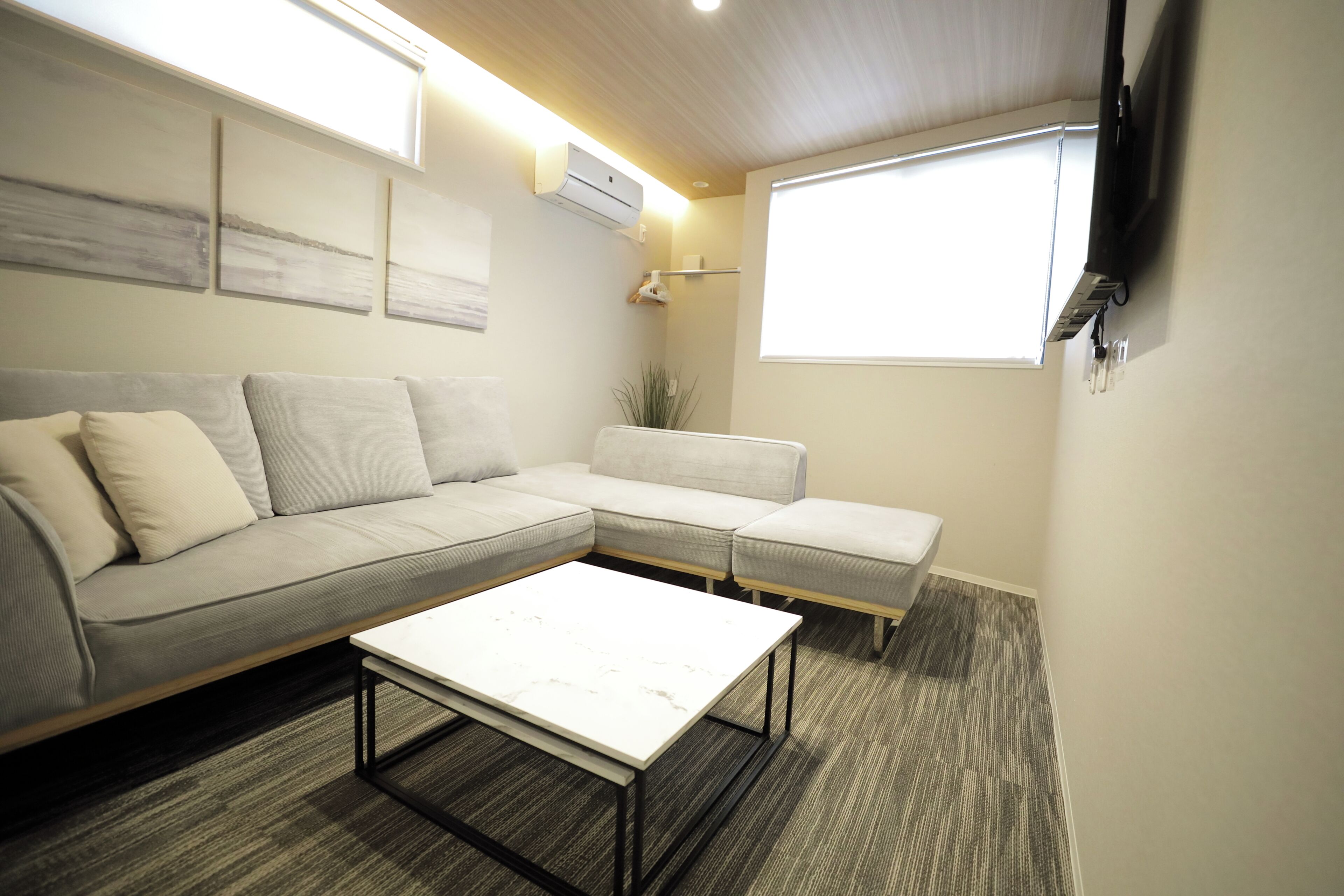 A modern living room with a sectional sofa, a coffee table, and a large window providing natural light.