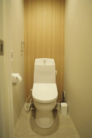 Eine Standardtoilette in einem Badezimmer mit Holztür und gefliestem Boden.