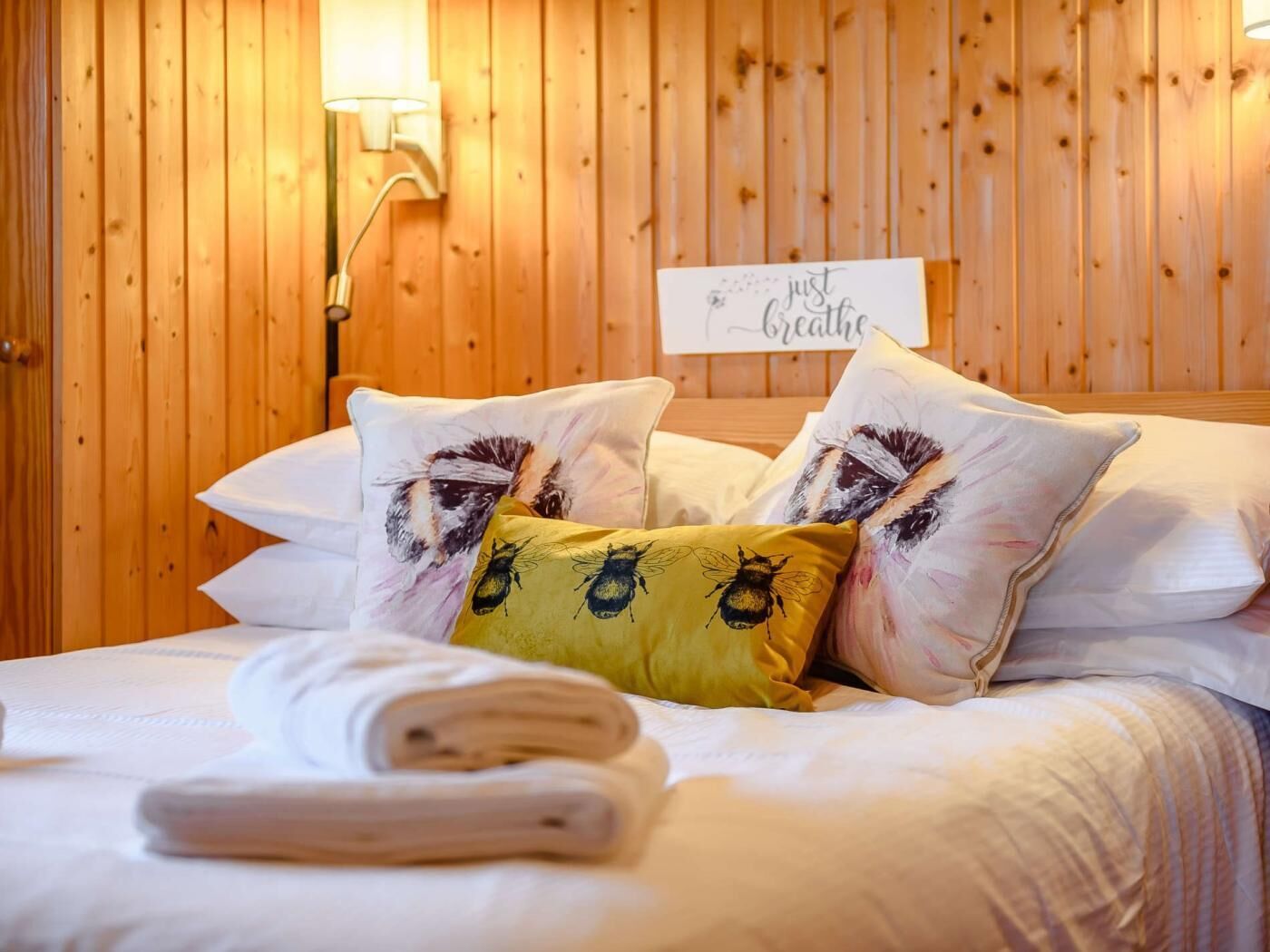 Ein Zimmer mit Holzwänden, einem Bett, Kissen, einem Schild und einer Wandlampe.